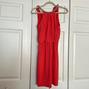 Orange short dress with gold neck embellishment.